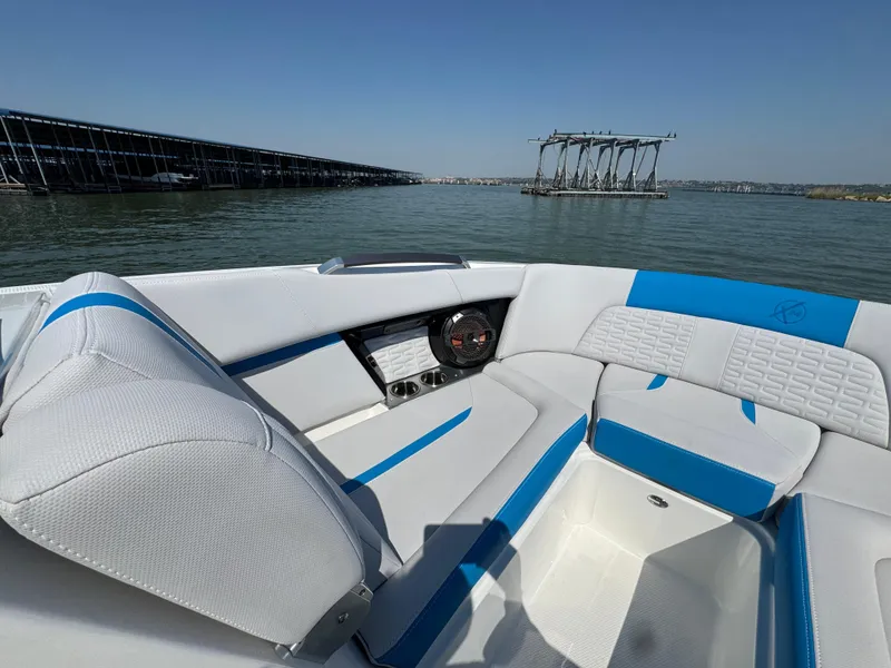 Slide: The Image of 2019 MasterCraft X24 boat interior with blue and white seating on a calm lake. - 14