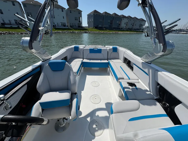 Slide: The Image of 2019 MasterCraft X24 boat interior with blue and white seating, docked near waterfront homes. - 15