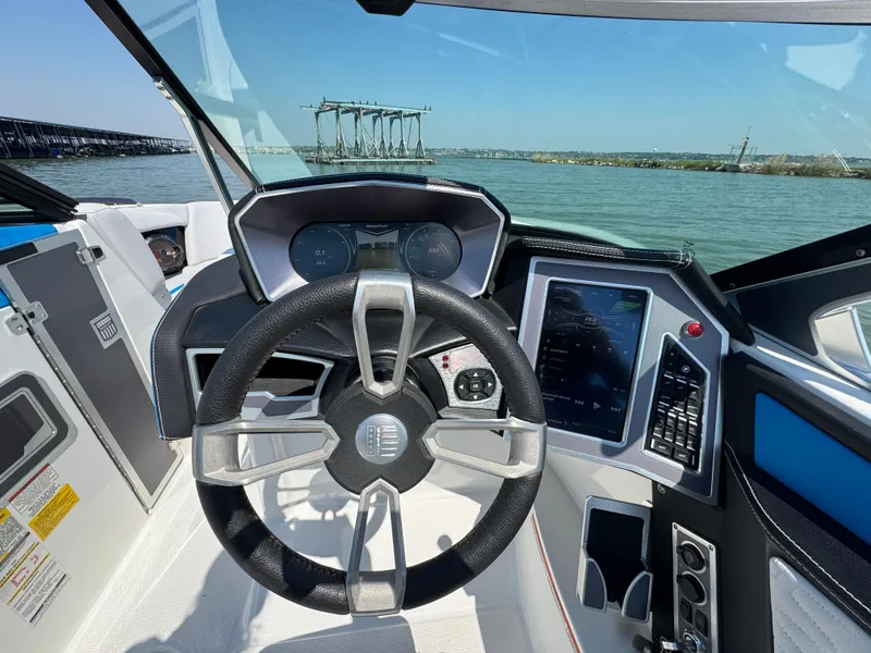Slide: The Image of 2019 MasterCraft X24 boat cockpit with steering wheel and digital controls on a sunny day. - 18