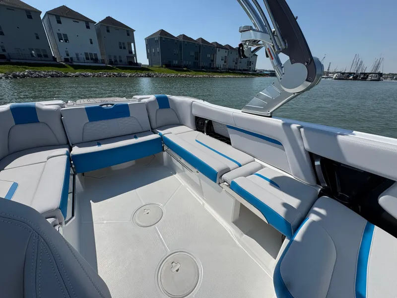 Slide: The Image of 2019 MasterCraft X24 boat interior with blue and white seating, docked near waterfront homes. - 20