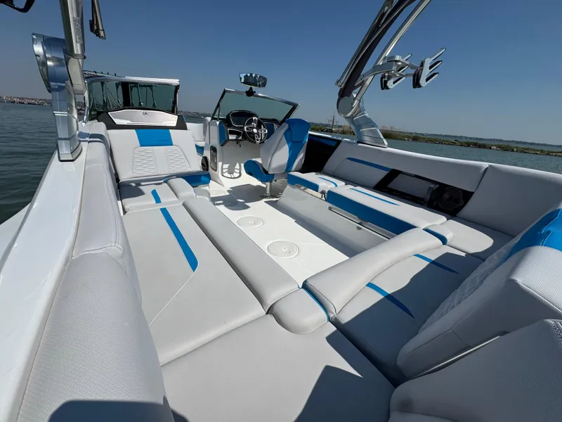 Slide: The Image of 2019 MasterCraft X24 boat interior with blue and white seating on a sunny day. - 21