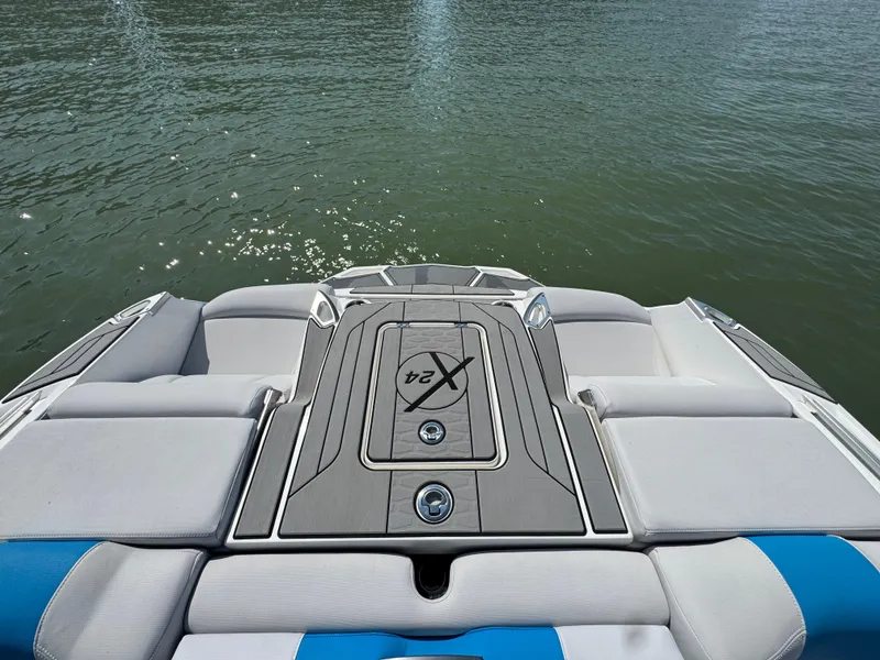 Slide: The Image of 2019 MasterCraft X24 boat with cushioned seating, viewed from the rear on water. - 23