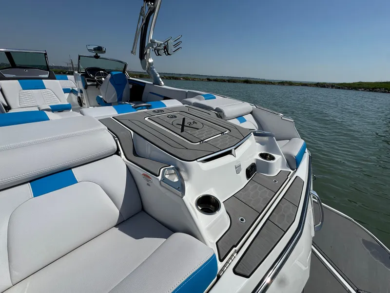 Slide: The Image of 2019 MasterCraft X24 boat interior with blue and white seating on a sunny day. - 24
