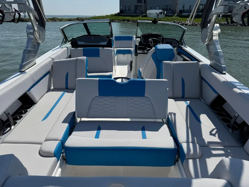 Slide: The Image of 2019 MasterCraft X24 boat interior with blue and white seating, docked on calm water. - 27
