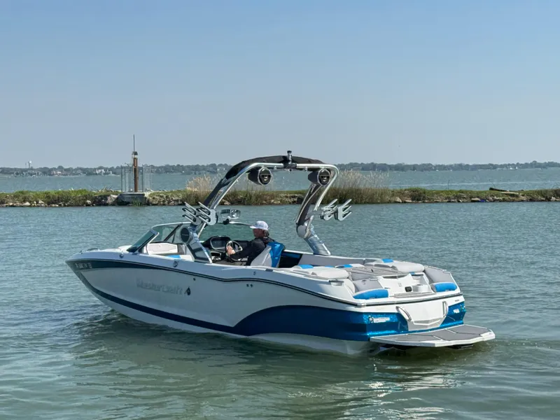 Slide: The Image of 2019 MasterCraft X24 boat cruising on a calm lake with a clear sky. - 4