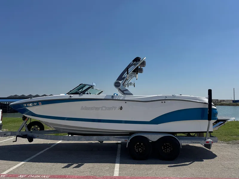 Slide: The Image of 2019 MasterCraft X24 boat on trailer, parked near a waterfront. - 7