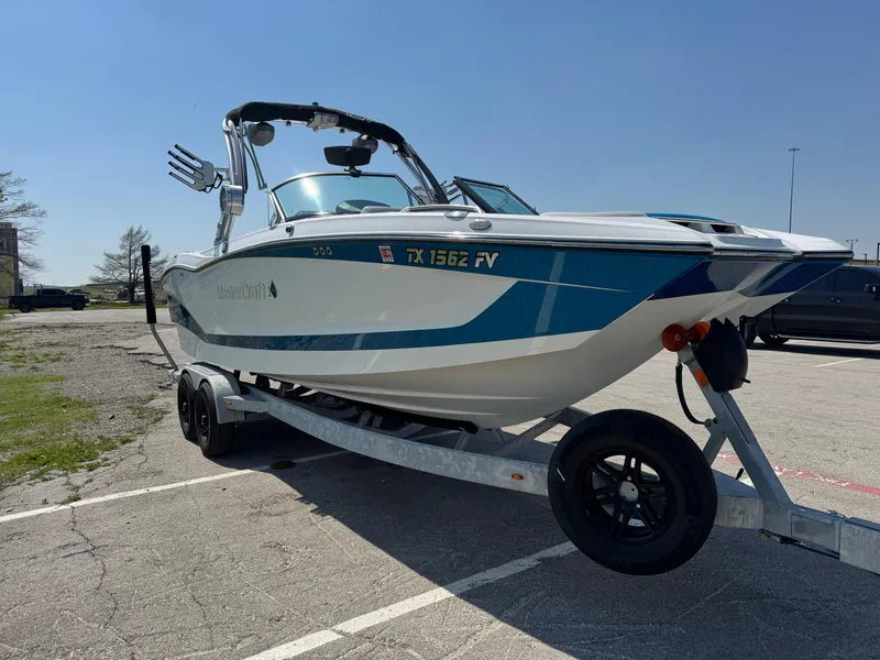 Slide: The Image of 2019 MasterCraft X24 boat on trailer in parking lot under clear sky. - 9