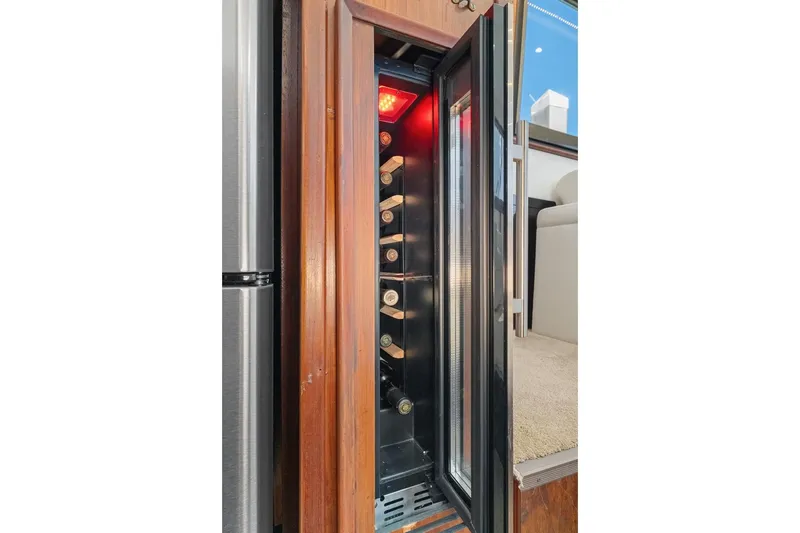 Slide: The Image of Wine cooler inside 1978 Hatteras 45 Convertible yacht, showcasing bottles and elegant wood finish. - 39