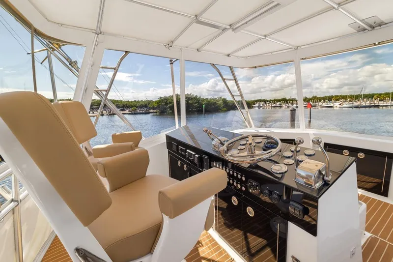 Slide: The Image of 1978 Hatteras 45 Convertible yacht helm with tan seats and scenic marina view. - 45