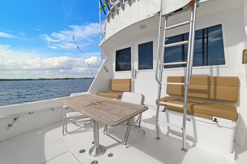 Slide: The Image of 1978 Hatteras 45 Convertible yacht deck with seating, table, and ladder, overlooking serene waters. - 51