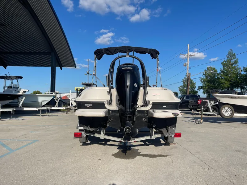 Slide: The Image of 2017 Bayliner Element E16 boat on trailer, parked outdoors under clear blue sky. - 2