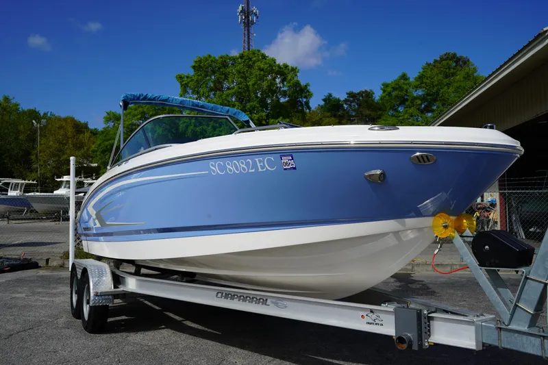 Slide: The Image of 2023 Chaparral 21 SSi OB boat on trailer, blue and white design, parked outdoors. - 2
