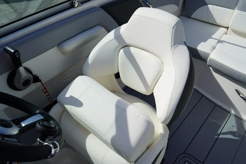 Slide: The Image of 2023 Chaparral 21 SSi OB boat interior with white captain's chair and steering wheel. - 21