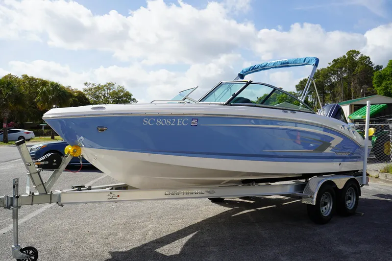 Slide: The Image of 2023 Chaparral 21 SSi OB boat on trailer, parked outdoors under a partly cloudy sky. - 4