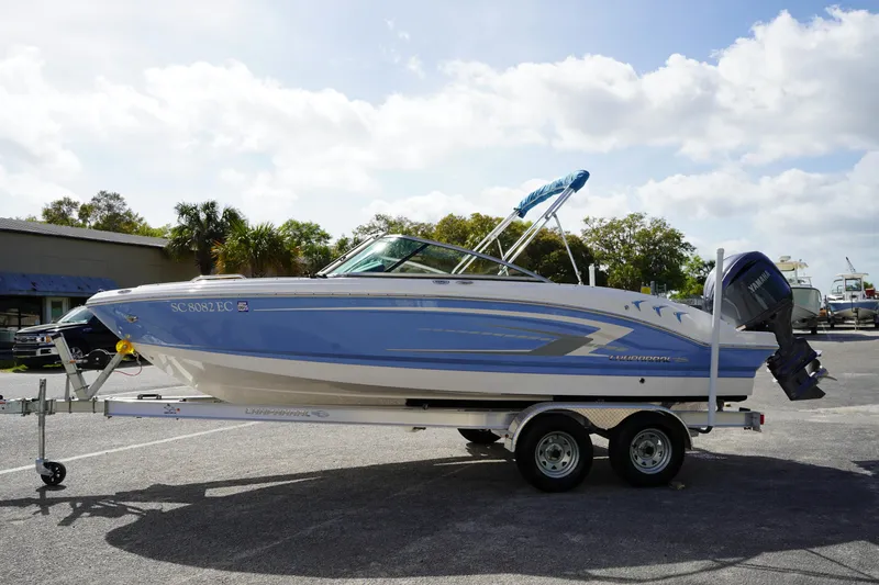 Slide: The Image of 2023 Chaparral 21 SSi OB boat on trailer, parked outdoors under cloudy sky. - 5