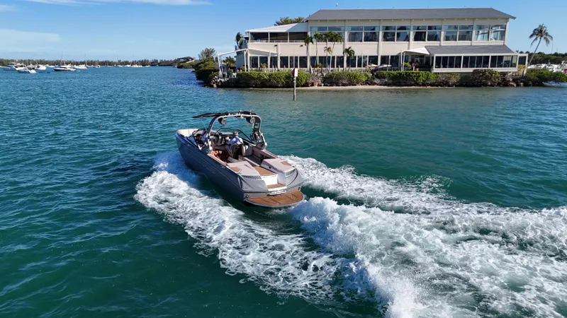 Slide: The Image of 2018 Nautique Super Air Nautique G25 cruising near waterfront building. - 11