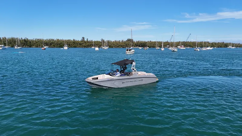 Slide: The Image of 2018 Nautique Super Air Nautique G25 boat on a calm blue lake with sailboats. - 20
