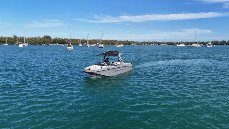 Slide: The Image of 2018 Nautique Super Air Nautique G25 cruising on a sunny, blue lake with sailboats in the background. - 21