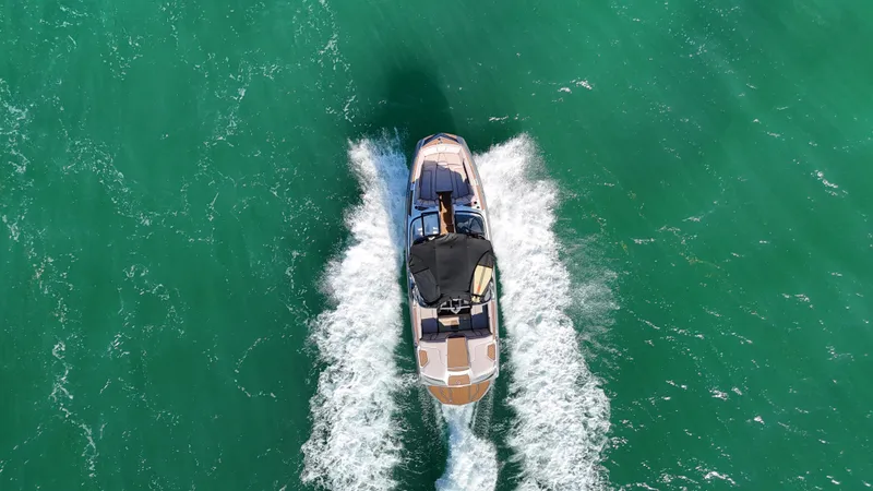 Slide: The Image of 2018 Nautique Super Air Nautique G25 boat cruising on turquoise water, aerial view. - 24