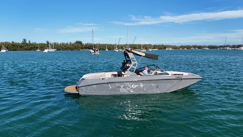 Slide: The Image of 2018 Nautique Super Air Nautique G25 boat on calm water under clear blue sky. - 27