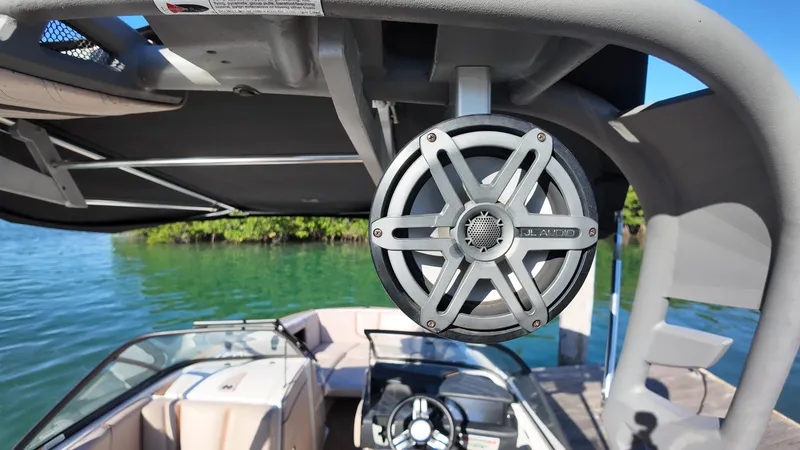 Slide: The Image of 2018 Nautique Super Air Nautique G25 boat with tower speaker, docked on clear water. - 33