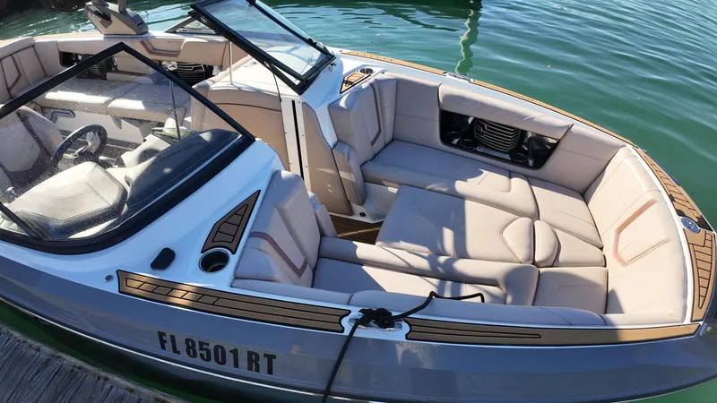 Slide: The Image of 2018 Nautique Super Air Nautique G25 boat with spacious seating, docked on calm water. - 37