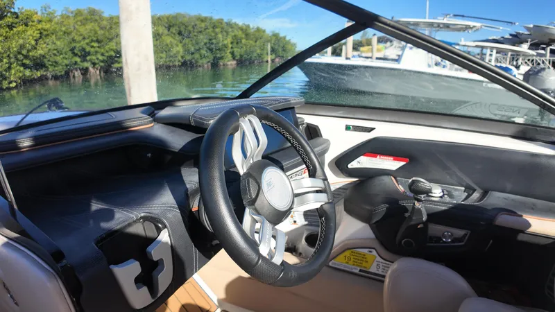 Slide: The Image of 2018 Nautique Super Air Nautique G25 cockpit with sleek steering wheel and modern controls. - 49