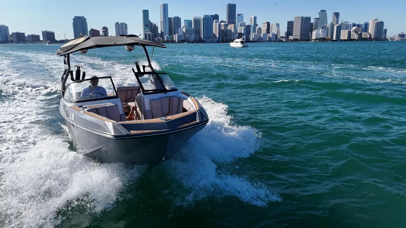 Slide: The Image of 2018 Nautique Super Air Nautique G25 cruising on water with city skyline in background. - 7