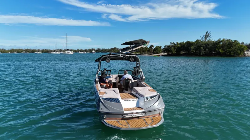 Slide: The Image of 2018 Nautique Super Air Nautique G25 boat cruising on a sunny day in clear blue waters. - 9