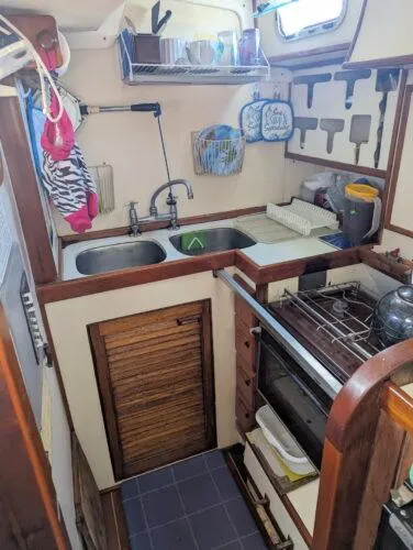 Slide: The Image of Compact kitchen in a 1990 Bruce Roberts 43 Mauritius sailboat, featuring a stove, sink, and storage. - 21
