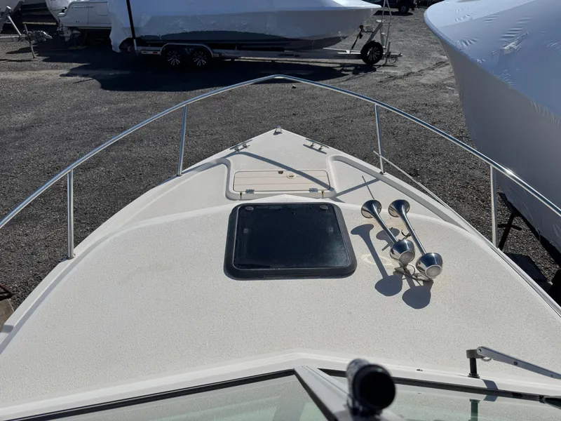 Slide: The Image of 2000 Parker 2110 Walkaround boat deck with railing and hatch, parked on gravel. - 11