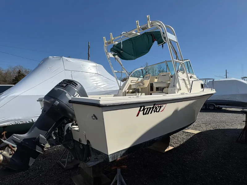 Slide: The Image of 2000 Parker 2110 Walkaround boat with outboard motor, parked on a gravel lot. - 3
