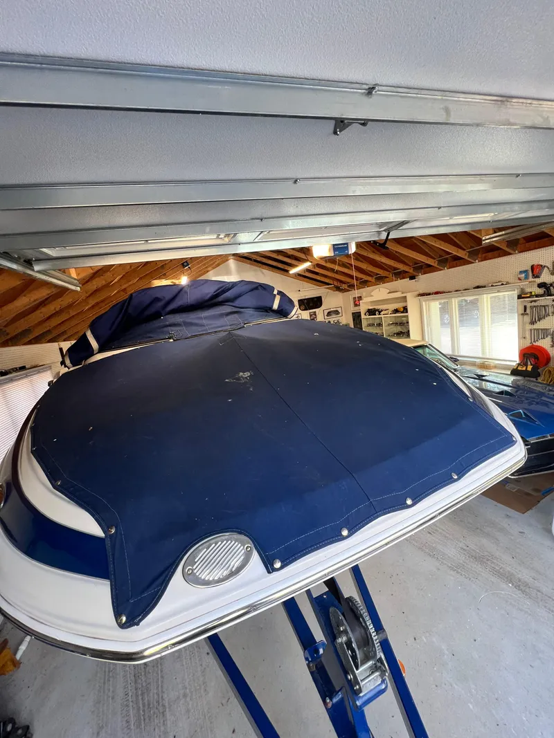 Slide: The Image of 2012 Crownline E2 Eclipse boat with blue cover in a garage. - 13