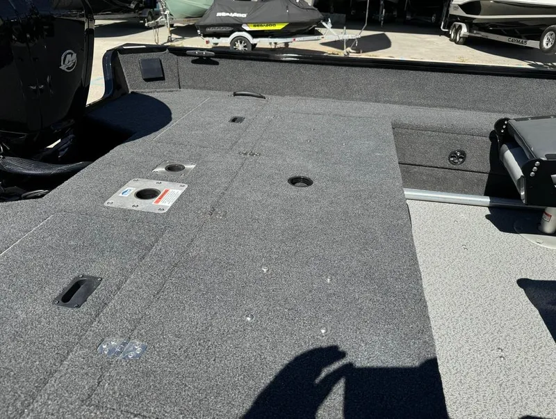 Slide: The Image of 2022 Lowe Fishing Machine 1675 WT interior with carpeted deck and storage compartments. - 14