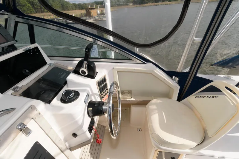 Slide: The Image of 1994 Grady-White Adventure 208 boat cockpit with steering wheel and controls, docked by the water. - 7
