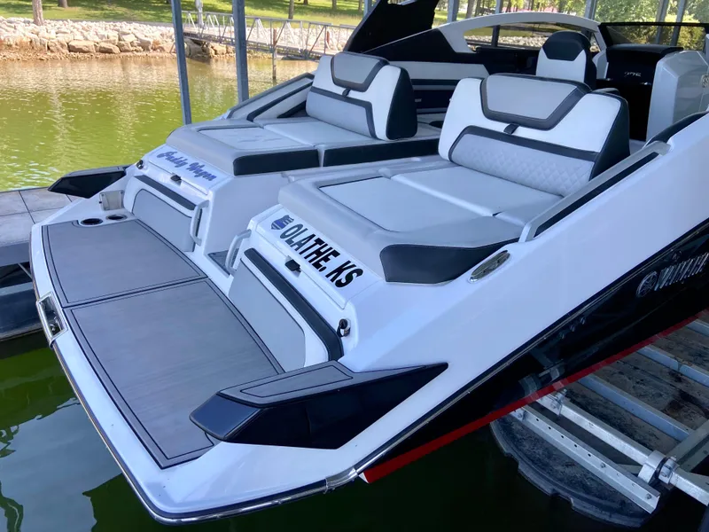 Slide: The Image of 2019 Yamaha Boats 275 SE with sleek seating and swim platform, docked by a serene lake. - 12
