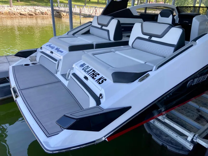 Slide: The Image of 2019 Yamaha Boats 275 SE with sleek seating, docked on a calm lake. - 13