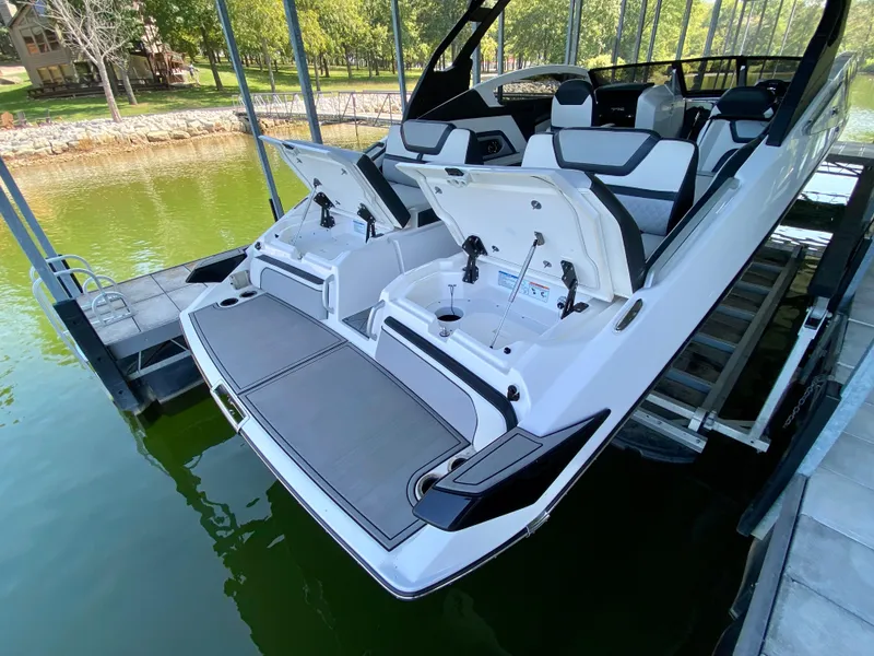 Slide: The Image of 2019 Yamaha Boats 275 SE docked, open storage compartments, sleek design, lake setting. - 15