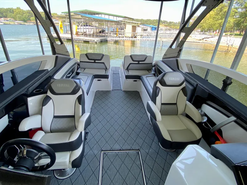 Slide: The Image of 2019 Yamaha Boats 275 SE interior with luxurious seating, docked by a serene lake. - 29