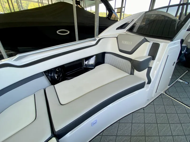 Slide: The Image of 2019 Yamaha Boats 275 SE interior with sleek white and gray seating in a marina setting. - 33