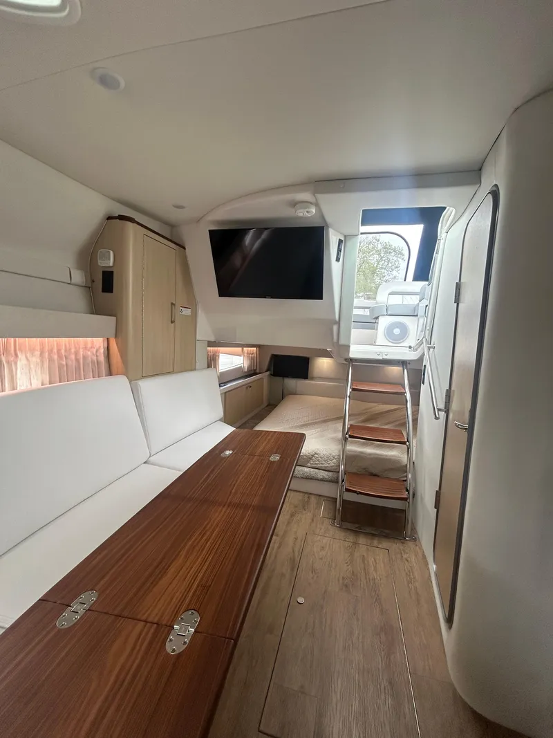 Slide: The Image of 2024 Regal 33 XO interior with modern seating, wooden table, and stairs to deck. - 8