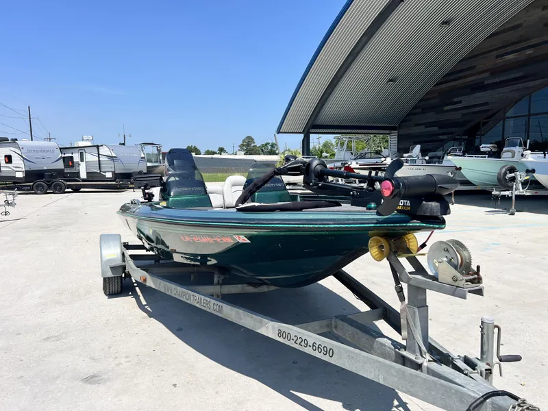 Slide: The Image of 1994 Skeeter 140 SLS boat on trailer, parked outdoors near modern building. - 15