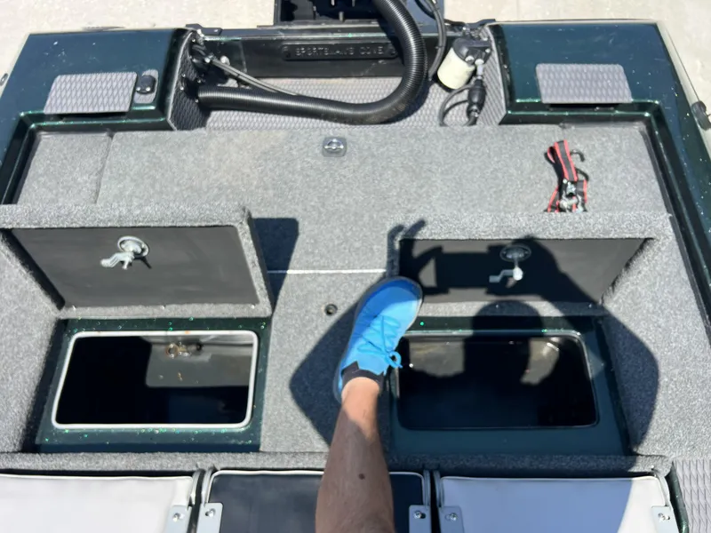 Slide: The Image of 1994 Skeeter 140 SLS boat interior with open storage compartments and a person wearing blue shoes. - 26