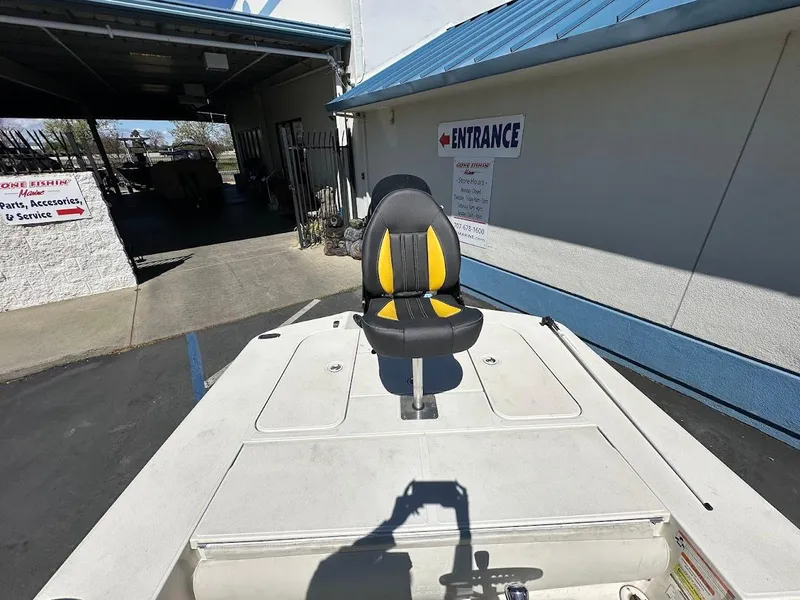 Slide: The Image of 2007 Ranger 191 Cayman boat with a black and yellow seat, parked near a building entrance. - 27