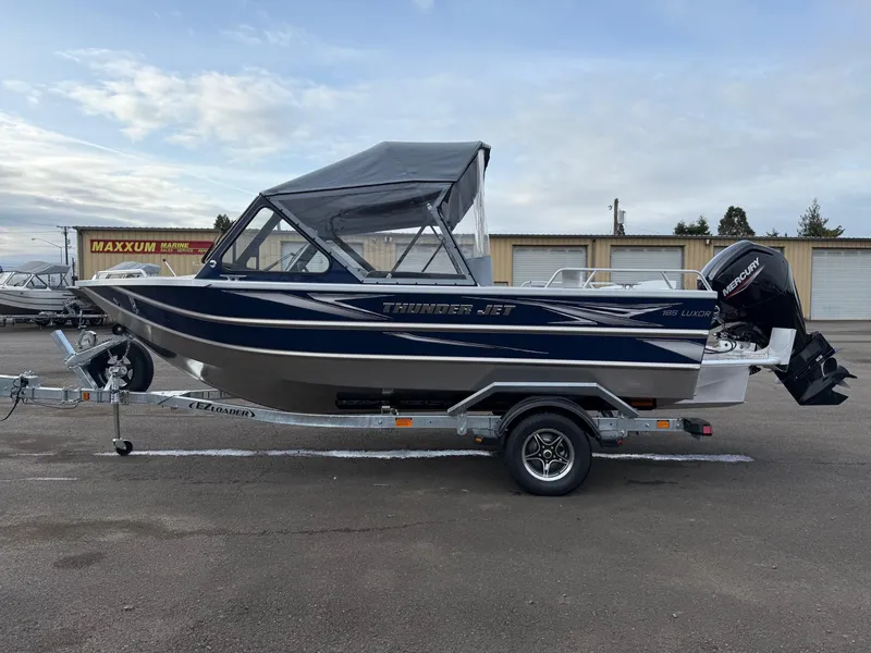 Slide: The Image of 2025 Thunder Jet 185 Luxor boat on trailer, blue and silver design, parked outdoors. - 5