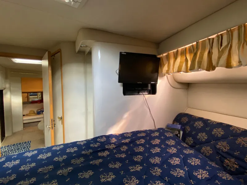 Slide: The Image of 1997 Sea Ray 450 Sundancer cabin with TV, patterned bedding, and cozy interior. - 13