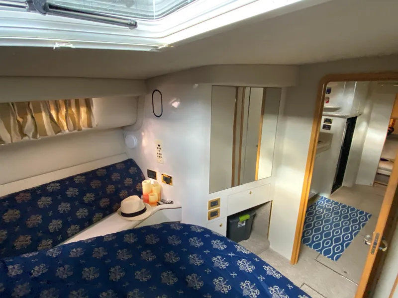 Slide: The Image of 1997 Sea Ray 450 Sundancer cabin interior with blue patterned bedding and natural light. - 14