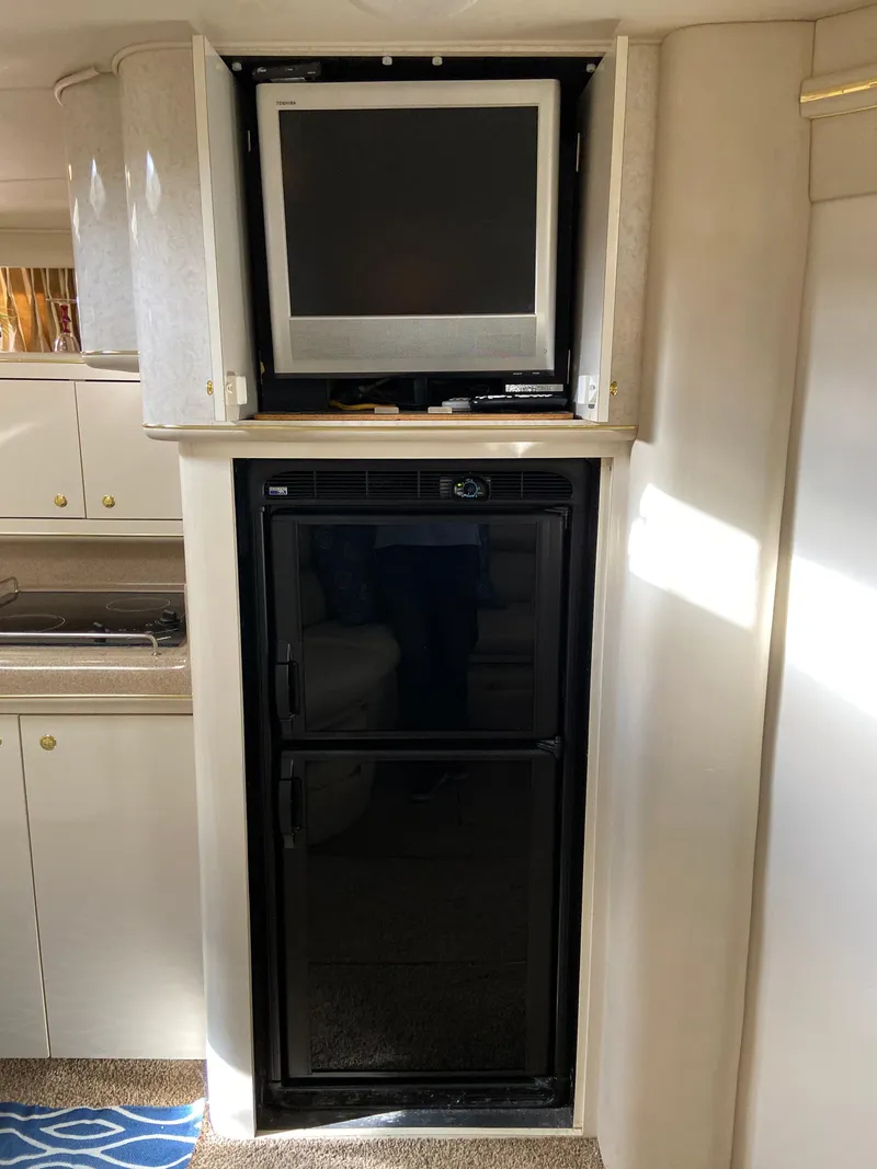 Slide: The Image of 1997 Sea Ray 450 Sundancer interior with TV and refrigerator. - 21