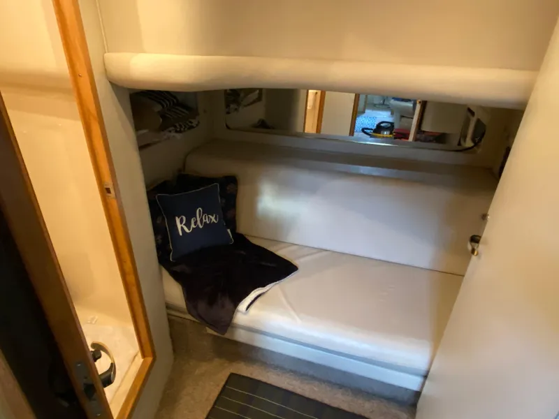 Slide: The Image of 1997 Sea Ray 450 Sundancer cabin interior with cozy bed and "Relax" pillow. - 22