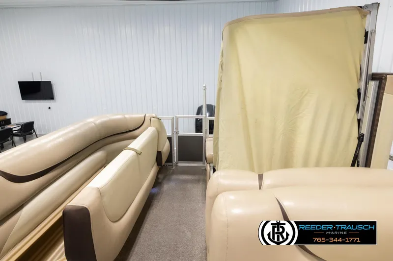 Slide: The Image of 2016 Sun Tracker 24 Party Barge interior with beige seating and canopy in showroom. - 17